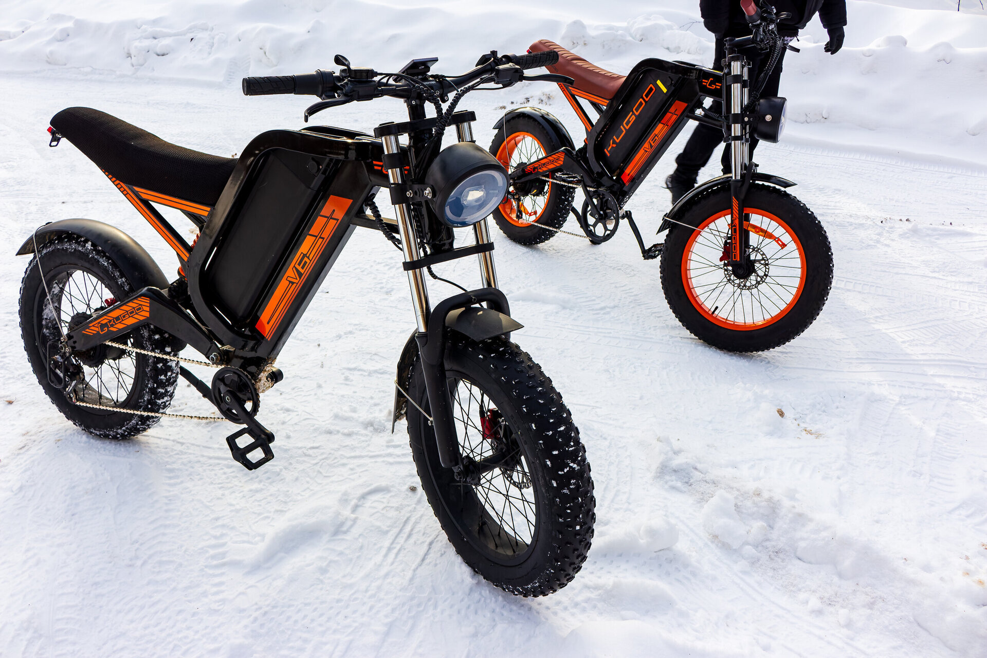 Two rugged Kugoo electric bikes with fat tires parked on a snowy winter path for a pair ride